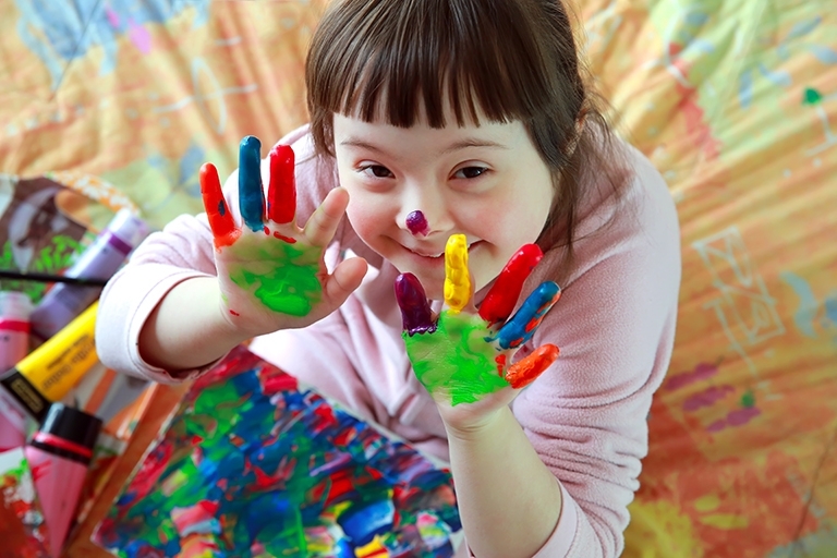 Girl having fun painting with paint over her hands.